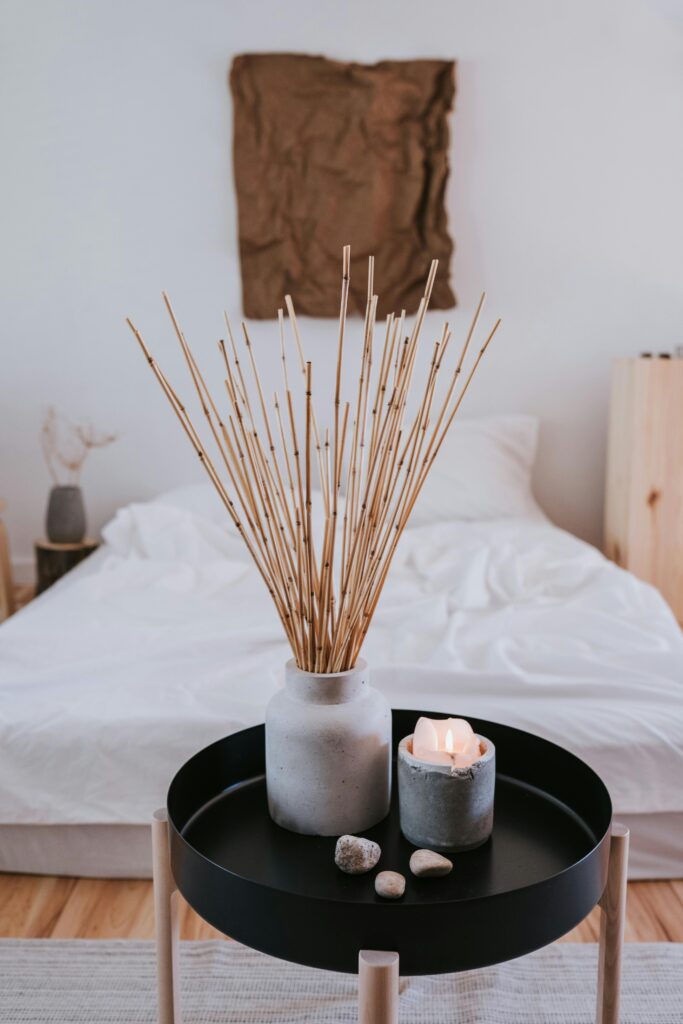A peaceful bedroom scene with a lit candle beside a bed, symbolising stillness, rest, and spiritual reflection.