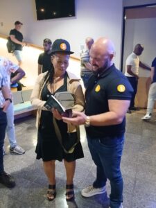 Eugene Marillier presenting her second book to Justin Harrison, founder of MoneyTribe21, who endorsed it.