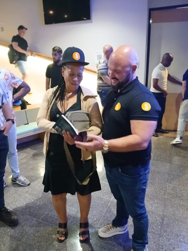Eugene Marillier presenting her second book to Justin Harrison, founder of MoneyTribe21, who endorsed it.
